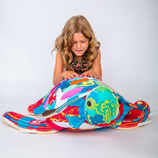 Child playing with a colourful turtle-shaped sculpture on a white background