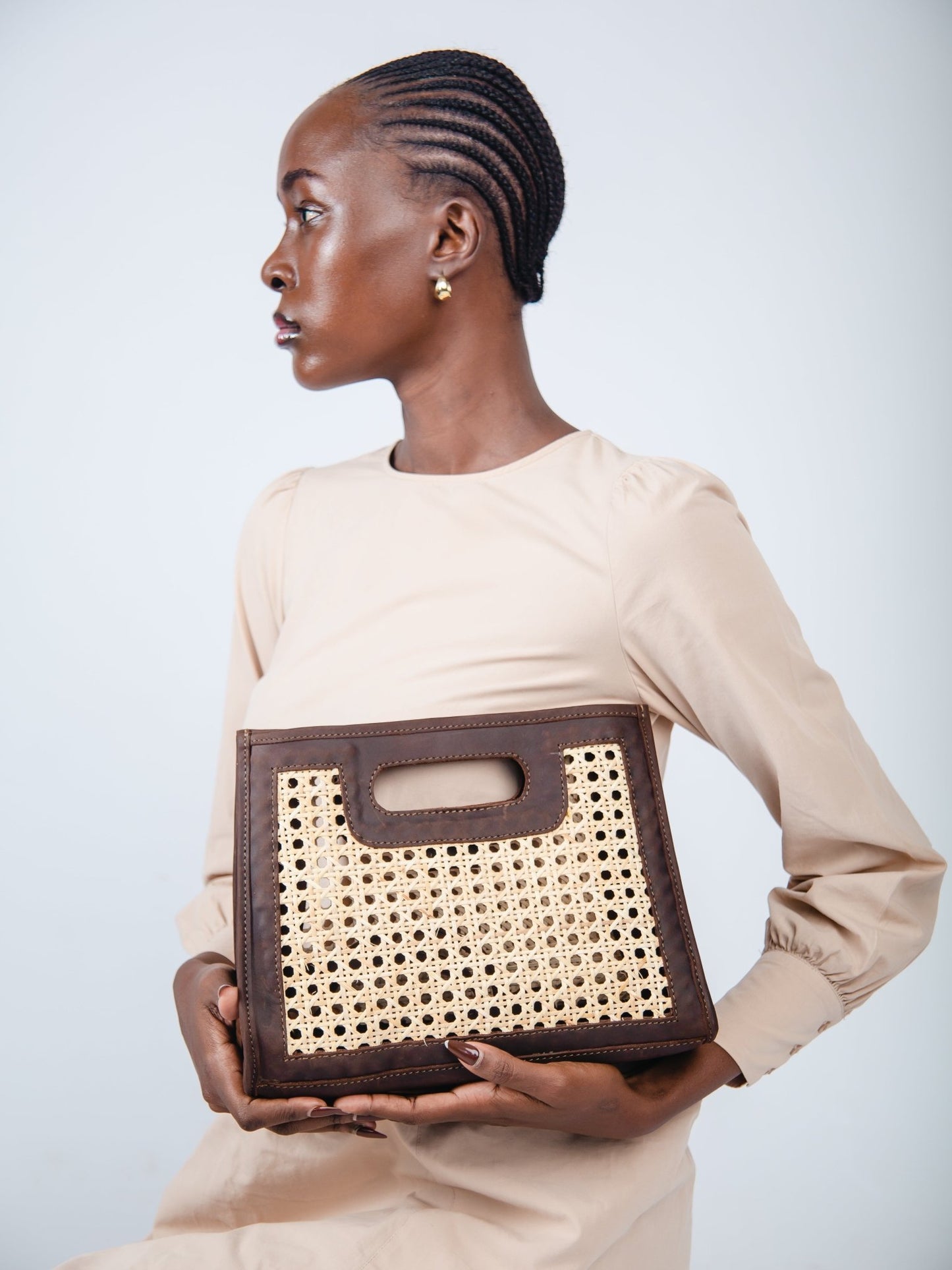 Woman holding a brown and beige handbag against a plain background
