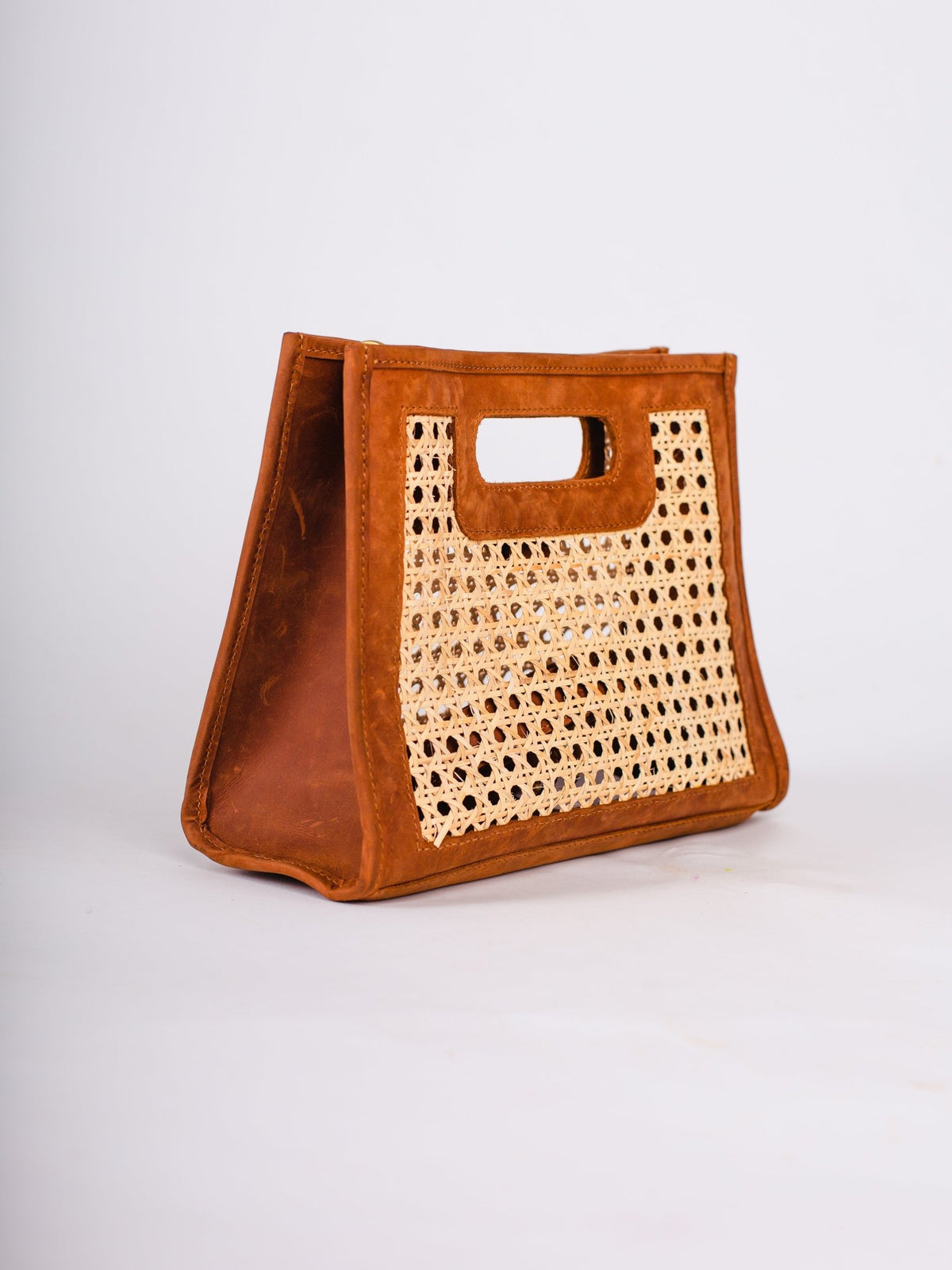 Brown leather tote bag with woven handle on a white background