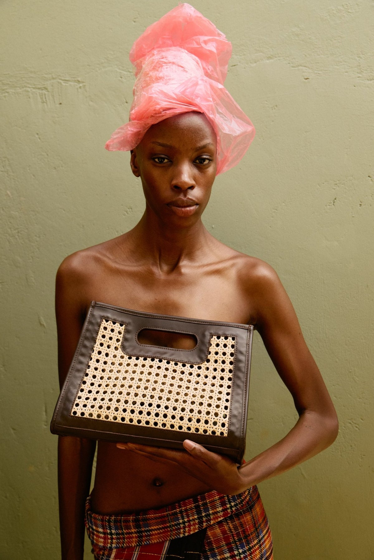 Woman holding a woven basket with a pink headscarf on a green background