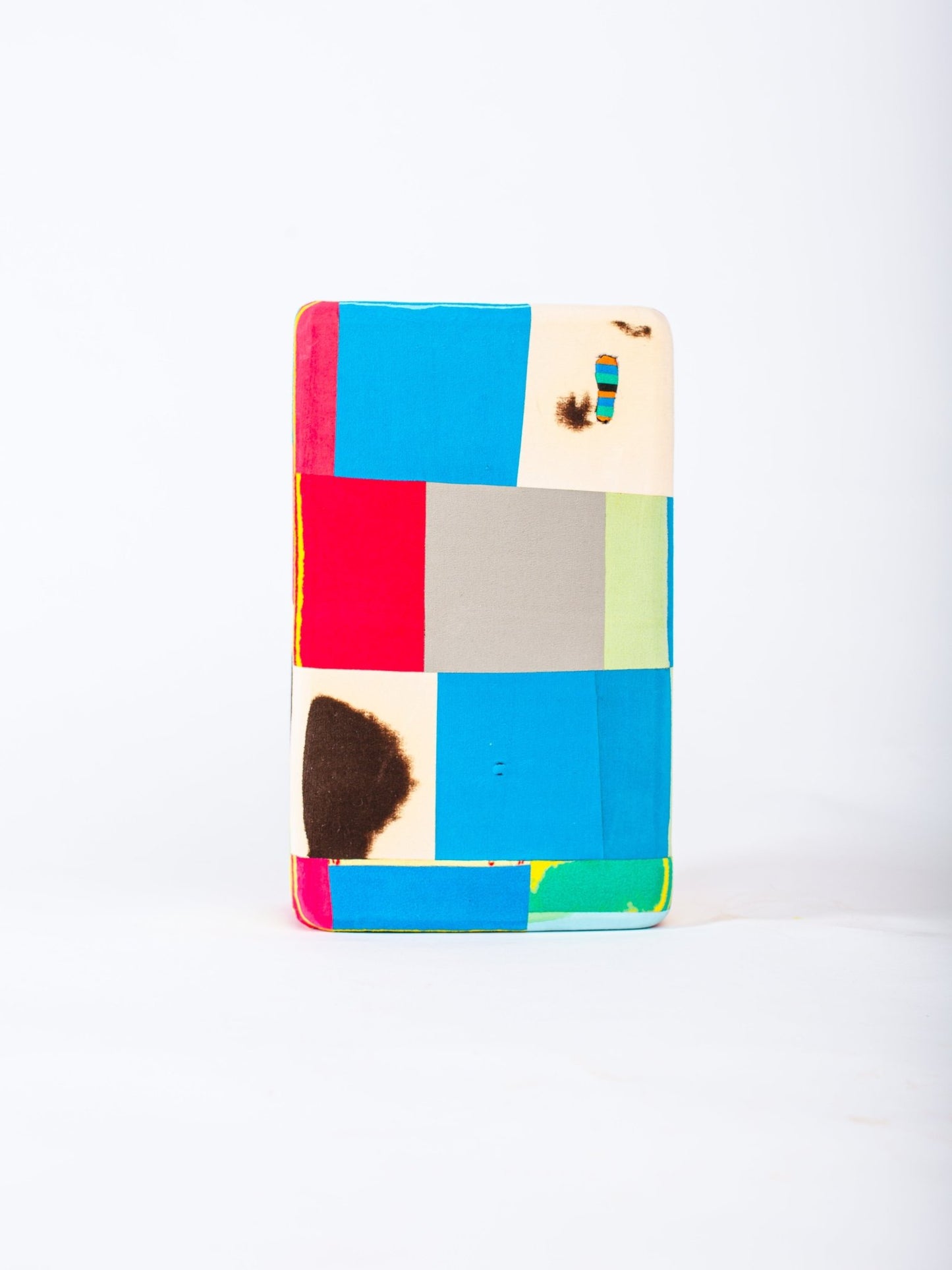 Colourful geometric patterned yoga block on a white background