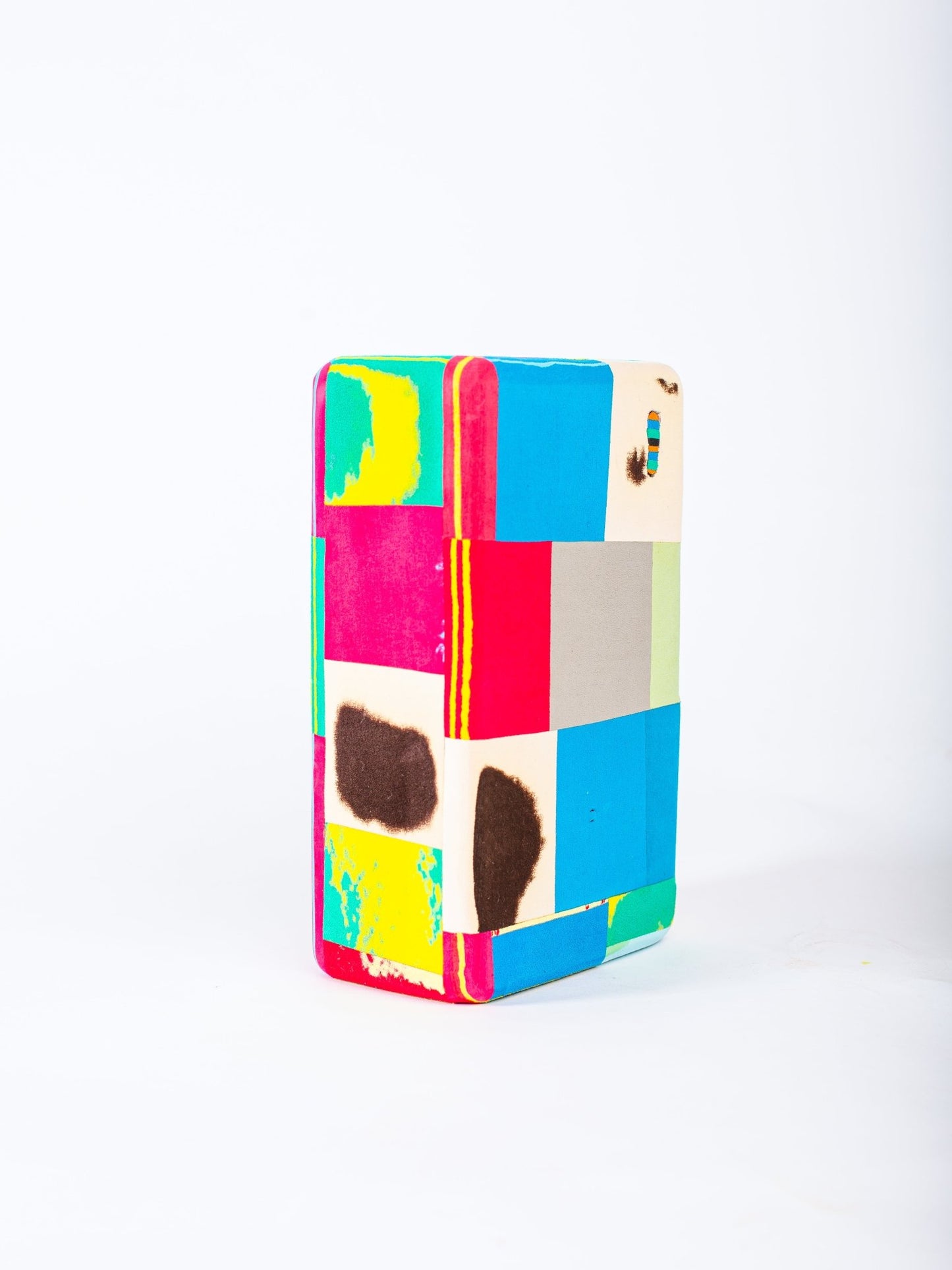 Colourful geometric patterned yoga block on a white background